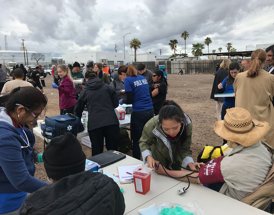 Street medicine volunteers providing care at an outdoor outreach table.