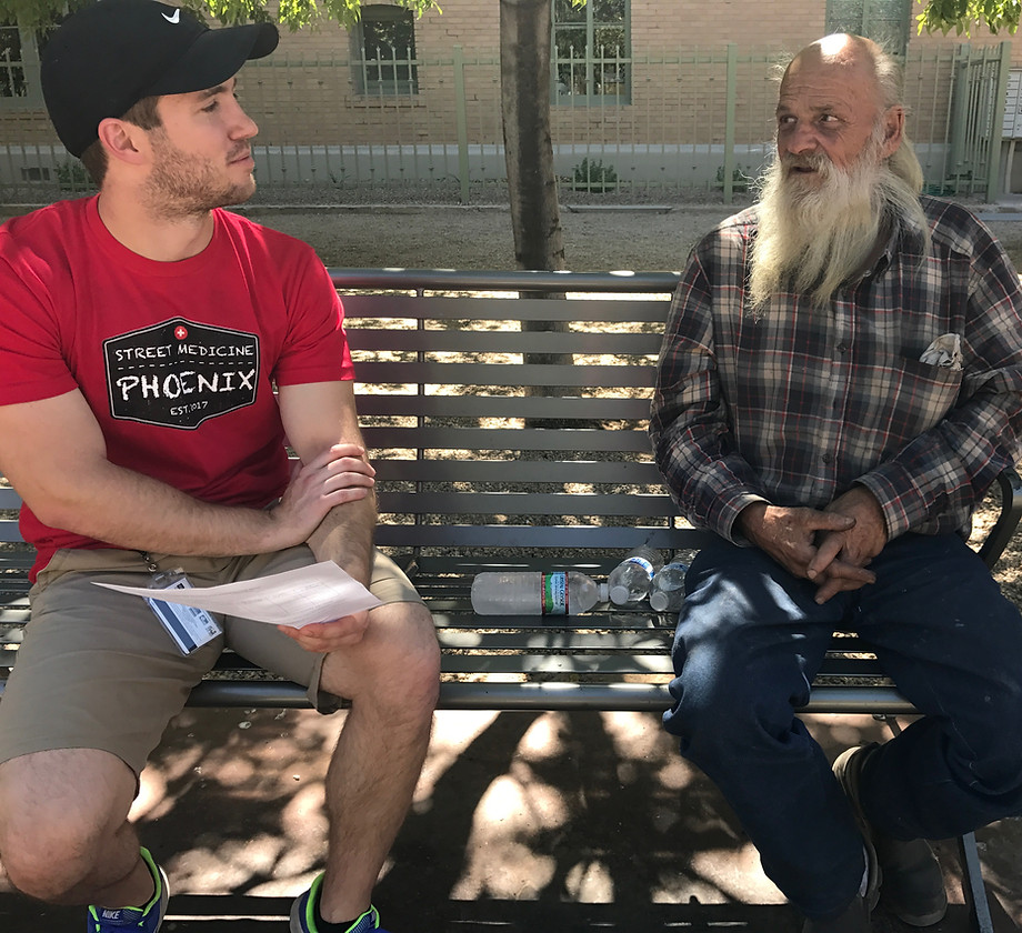 A street medicine volunteer speaking with a community member.